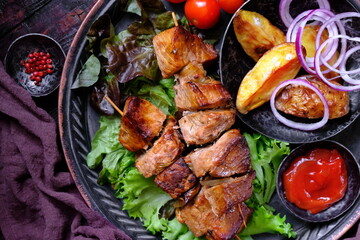 Skewers of Meat with sauce on wooden cutting board, ready to be served as summer party meal, view from above.