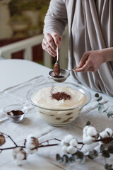 Step by step tiramisu. Decorating dessert with cacao powder.