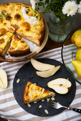 Slice of homemade pear pie and sliced fresh pear on black plate
