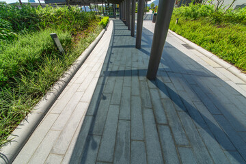 The glass walkways and lawns of the modern park in the city center are under the blue sky and white clouds.