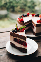 Mousse cake with berries on a wooden table. Chocolate cream cake with currants and cherries. Berry cake for birthday, wedding and other holidays.