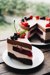 Mousse cake with berries on a wooden table. Chocolate cream cake with currants and cherries. Berry cake for birthday, wedding and other holidays.