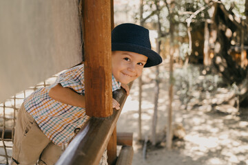 Baby boy in a blue hat and shirt smiling. In the park, in the summer.