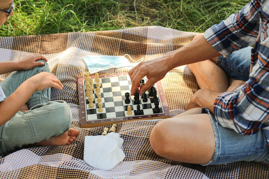 Father And Child Playing Chess Outdoors Top View Protective Masks In The Background Restart Of Normal Life After Coronavirus Pandemic.