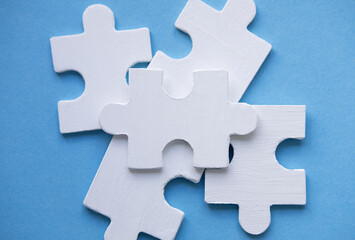 White Jigsaw Puzzle pieces on blue background top view. Concept for Unite. Symbol of association and connection, business strategy, completing, team support and help concept. Space for text on puzzle