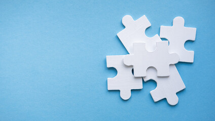 Obraz premium White Jigsaw Puzzle pieces on blue background top view. Concept for Unite. Symbol of association and connection, business strategy, completing, team support and help concept. Good banner