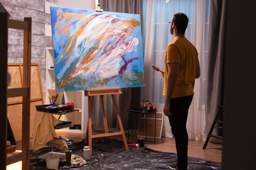 Creative young artist painting on large canvas in art workshop. Modern artwork paint on canvas,...