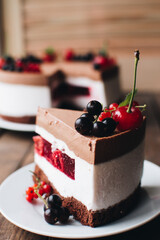 Mousse cake with berries on a wooden table. Chocolate cream cake with currants and cherries. Berry cake for birthday, wedding and other holidays.
