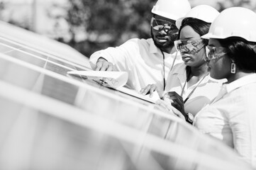 African american technician checks the maintenance of the solar panels. Group of three black engineers meeting at solar station.