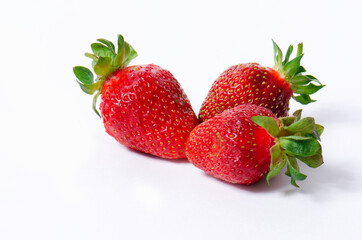 Three red strawberries on a white background close-up.