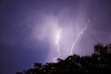 Naklejka na ściany i meble Lightning flashes in the night cloudy sky over the city. Storm.