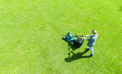 Beautiful girl cuts the lawn. Mowing lawns. Aerial view beautiful woman lawn mower on green grass....