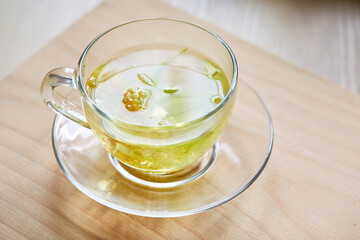 Transparent glass cup of herbal tea with linden flowers on a wooden background