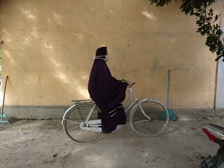 woman in hijab is riding a bicycle