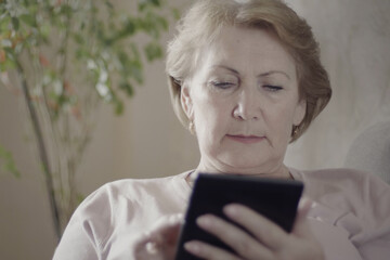 Beautiful middle age woman working from home, using her tablet computer