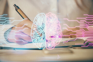 Double exposure of woman's writing hand on background with brain hologram. Concept of brainstorming.