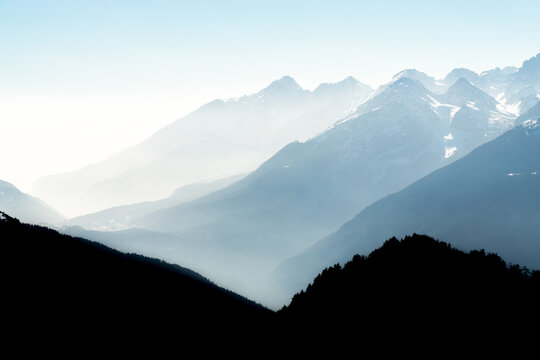 Spectacular view of mountain ranges silhouettes and fog in valleys. View from Top of Mount Corno di Tres, Tresner Horn. Trentino, South Tyrol, Alps, Italy.