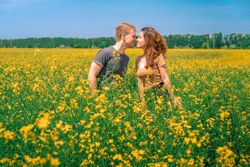 A young man and woman embrace in a Sunny yellow rapeseed field, the concept of travel and freedom, a bright banner for summer