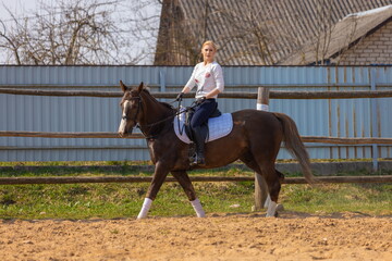 Girl riding a horse gallops in a paddock on a ranch