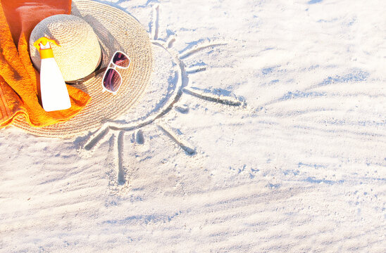 Sand Texture With Hat, Towel, Sunscreen And Sunglasses On The A Beach.