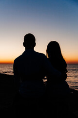 Loving couple in white clothes during a honeymoon at sea walk on the sand at a photoshoot Love Story, ocean coast, beach, silhouette