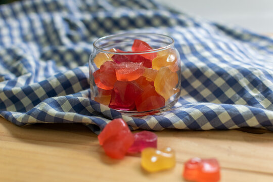 Colorful Heart form Jelly in the Glass Jar on the Wooden Table Decorate with Scottish Pattern Fabric