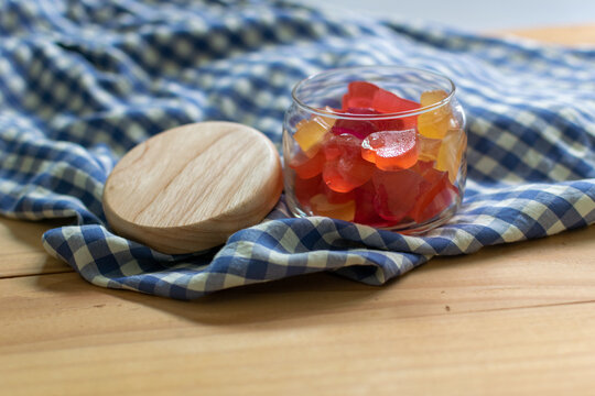 Colorful Heart form Jelly in the Glass Jar on the Wooden Table Decorate with Scottish Pattern Fabric