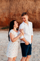 Loving couple in white clothes during a honeymoon at sea walk on the sand at a photoshoot Love Story, ocean coast, beach