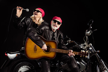 Obraz na płótnie Canvas Photo of aged bikers man lady duet couple sit chopper moto rock bike festival meeting play sing guitar songs remember youth wear rocker leather jacket pants isolated black color background