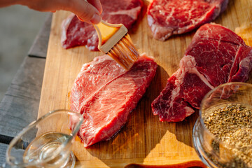 Marbled beef steak. Beef steaks on a wooden board in the sun. Nearby is butter and spices. The process of making steaks on the grill. Rib eye steak.