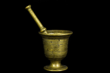 an old looking shiny metallic yellow brass made mortar pestile with black isolated background
