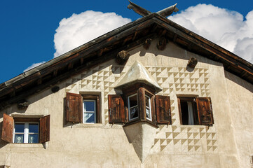 Closeup of an ancient house in Engadin valley with wooden windows and a small balcony, Graubunden canton, Switzerland, Europe