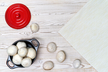 Champignons in a utensil on a table, light background, copy space, top view