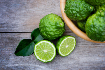 Fresh green Bergamot or kaffir lime fruit with slice isolated onrustic wood table background . Herbal medicine plant concept.