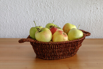Apples in a small basket on a wooden tabletop