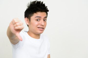 Portrait of young Asian man giving thumbs down