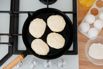 Cheesecakes are fried in a cast-iron pan. Woman sculpts a cheesecake. Cheesecakes are cooked in the home kitchen.