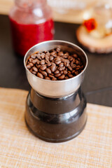 coffee beans poured into a coffee grinder