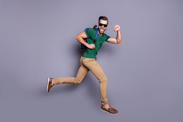 Full length profile side photo of excited guy jump run enjoy summer weekend tour hold backpack wear...