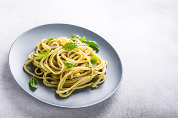 Homemade pasta, spaghetti, linguine with green pesto and basil. Italian healthy food concept with copy space.