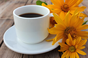 Сup of coffee and yellow flowers on wooden table. Summer lifestyle