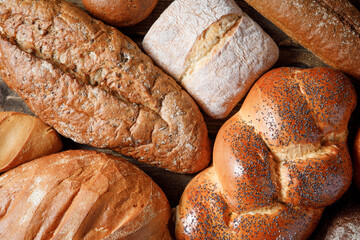 Bakery background - variety of loaves of bread and buns on wooden table