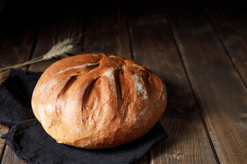 Homemade crusty loave of wheat bread on wooden background