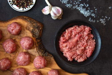 Homemade minced meat in a black bowl with spices. Raw mince for cooking meatballs.