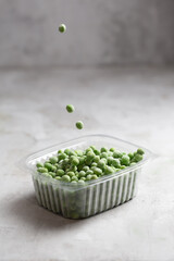Frozen pea in the storage boxe on the gray concrete background
