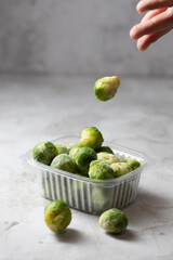 Frozen Brussels sprouts in the storage boxe on the gray concrete background