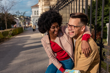 Smiling couple enjoying on vacation, young tourist having fun exploring city street during the day.