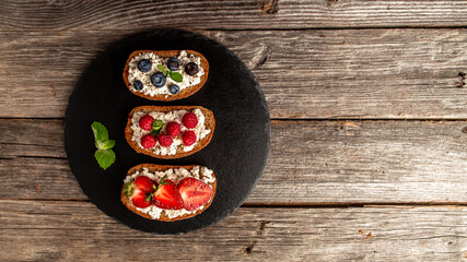 Assortment of fruit toasts with ricotta on stone background. banner, catering menu recipe place for text, top view