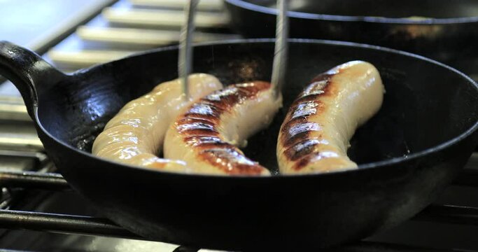 Close up of bratwursts in a pan.