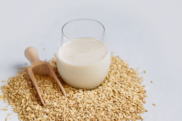 Vegan non dairy alternative oat milk in glass. Oat cereal in wooden spoo on stone table. concept of...